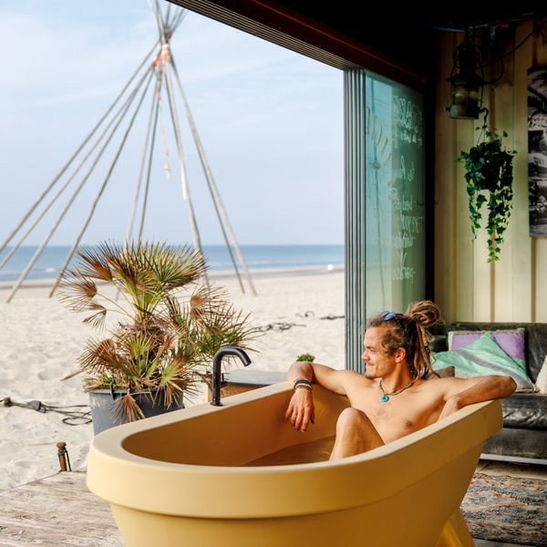 Man relaxing in a Sand Dune Gardentub outdoor bathtub near the beach