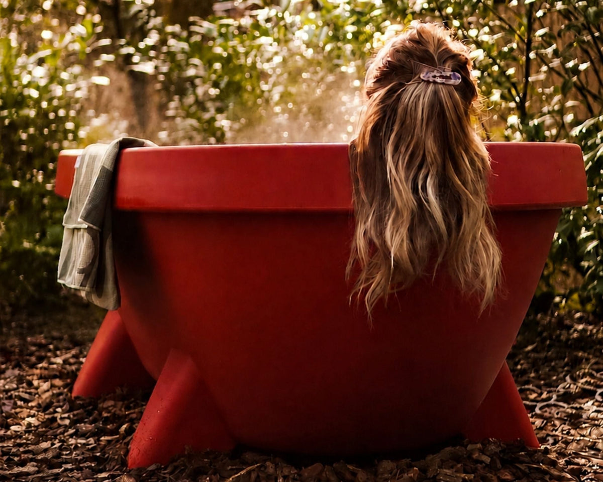 Vrouw ontspant in een terracotta Gardentub in een groene tuin.