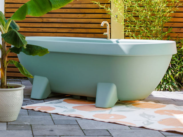 Lime Green Gardentub met gouden kraan op een sfeervol ingericht terras.