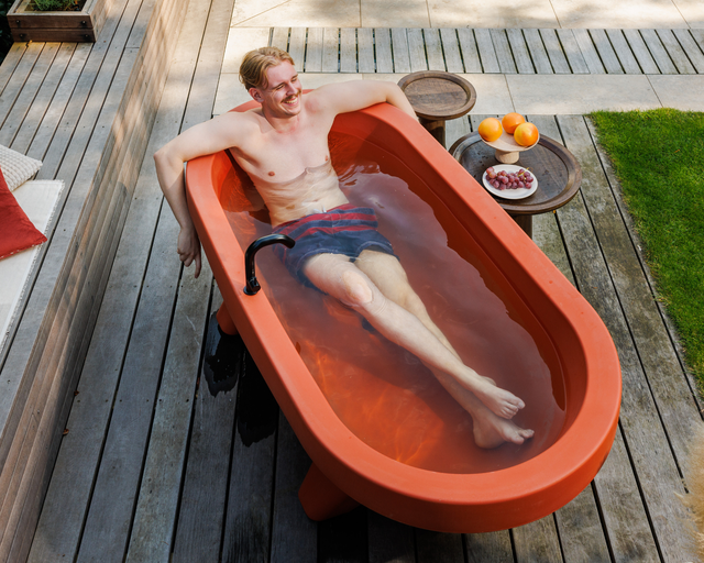 Man ontspant in een terracotta Gardentub op een houten terras.